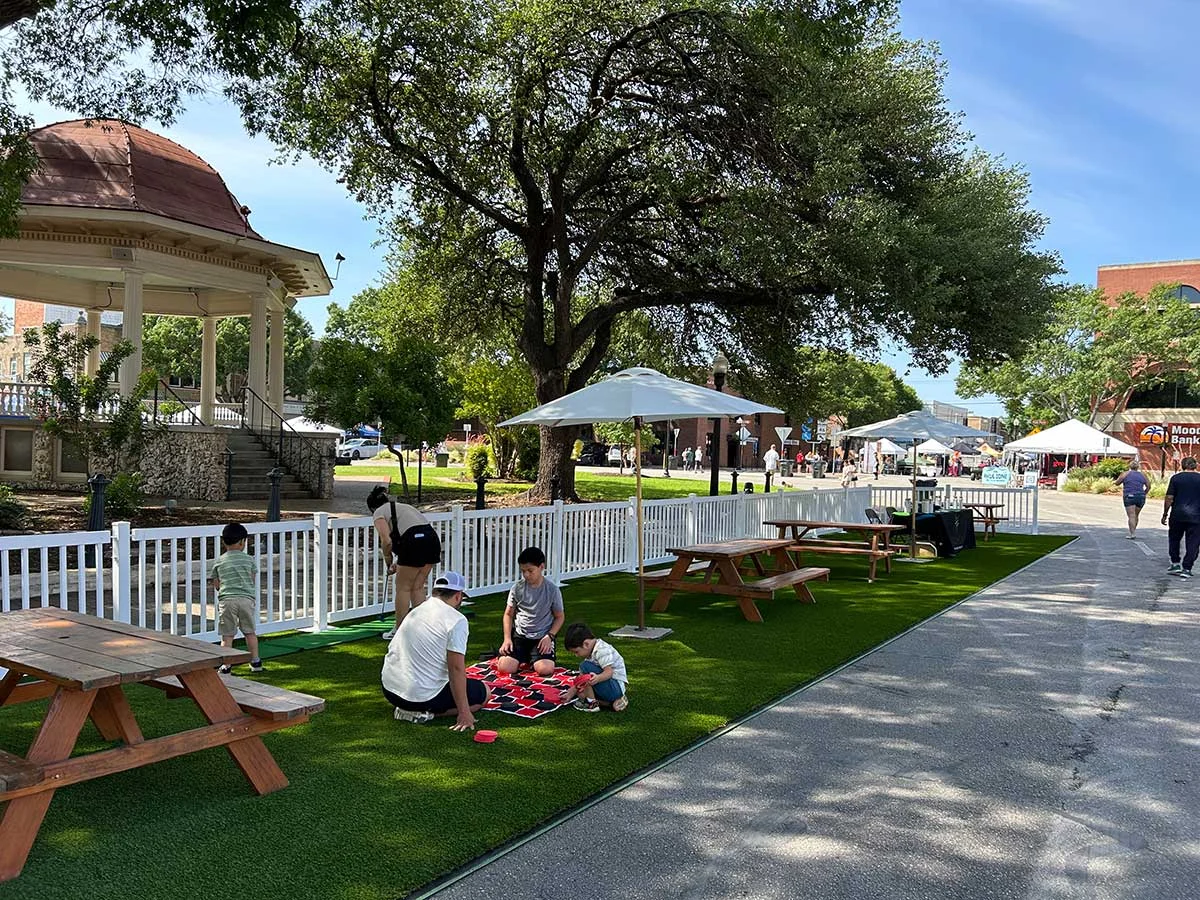 Family playing chess on the lawn under shady oak trees at Saengerfest 2025.
